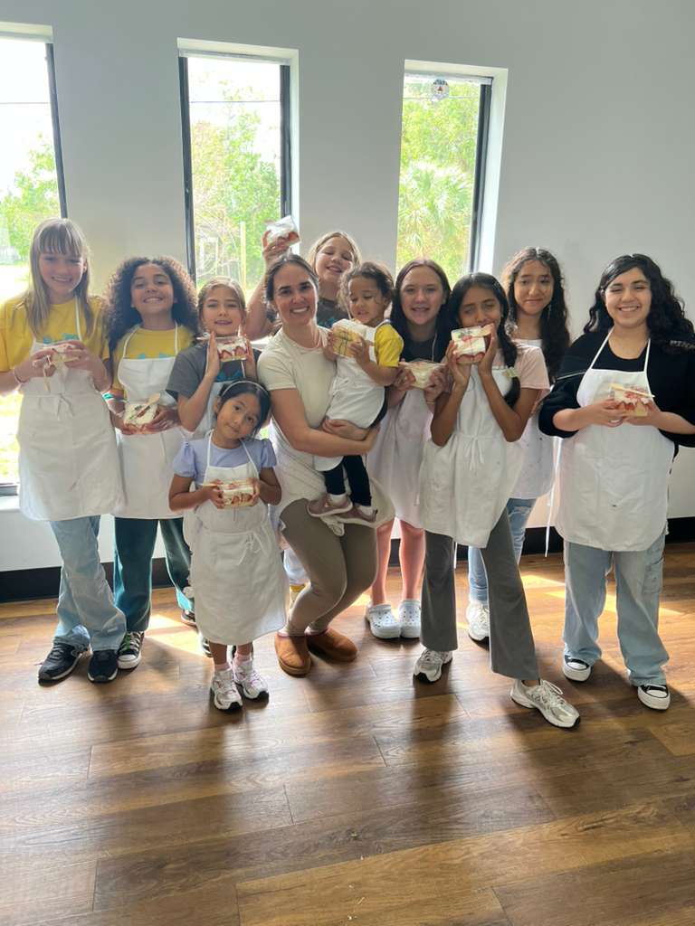 Connect students and instructor smiling together holding baked treats in aprons